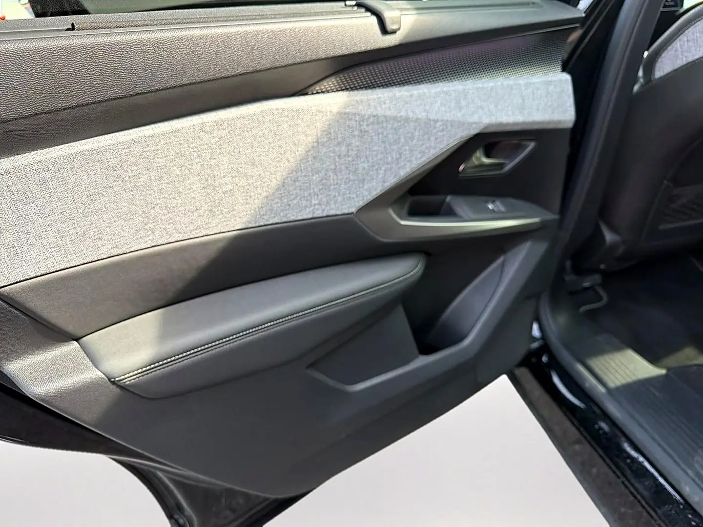 Vue rapprochée de la porte arrière droite noire du Peugeot 5008 Hybrid 145 GT avec habillage tissu gris et cuir noir.