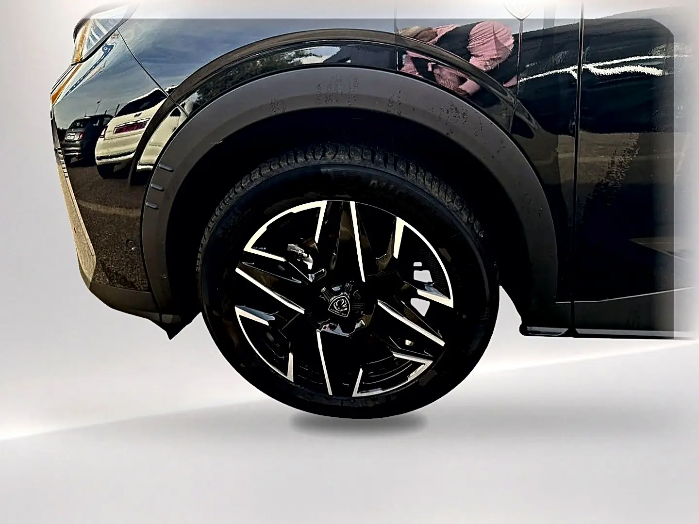Gros plan sur la roue avant gauche noire avec jante alu noire et argent du Peugeot 5008 Hybrid 145 GT e-DCS6 noir.