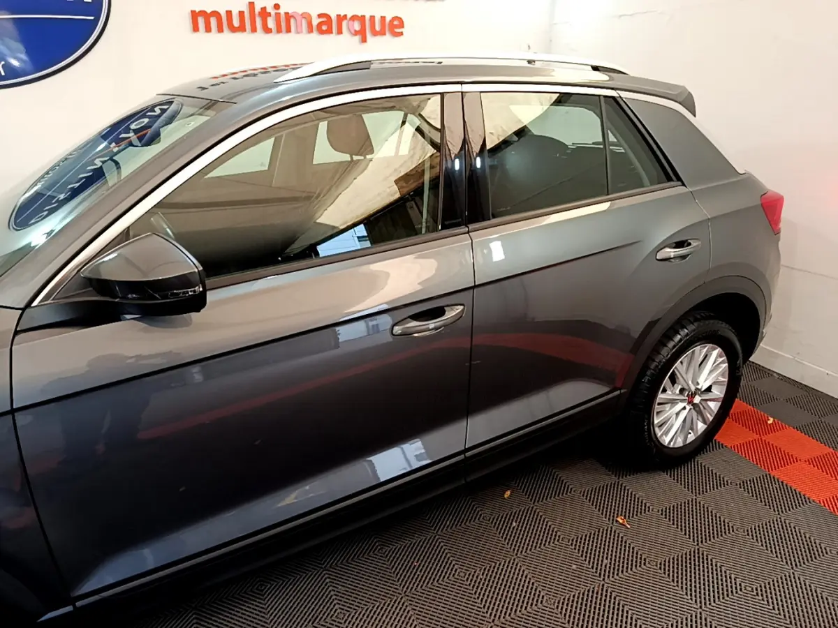 Vue latérale droite du Volkswagen T-Roc gris foncé, mettant en valeur les lignes épurées et les rétroviseurs noirs.