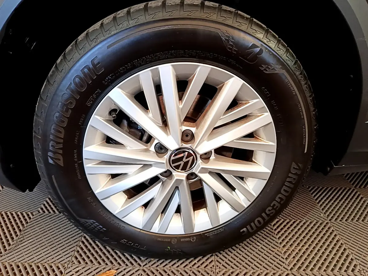 Gros plan sur la roue avant droite du Volkswagen T-Roc gris foncé, avec jante alliage et pneu Bridgestone visible.