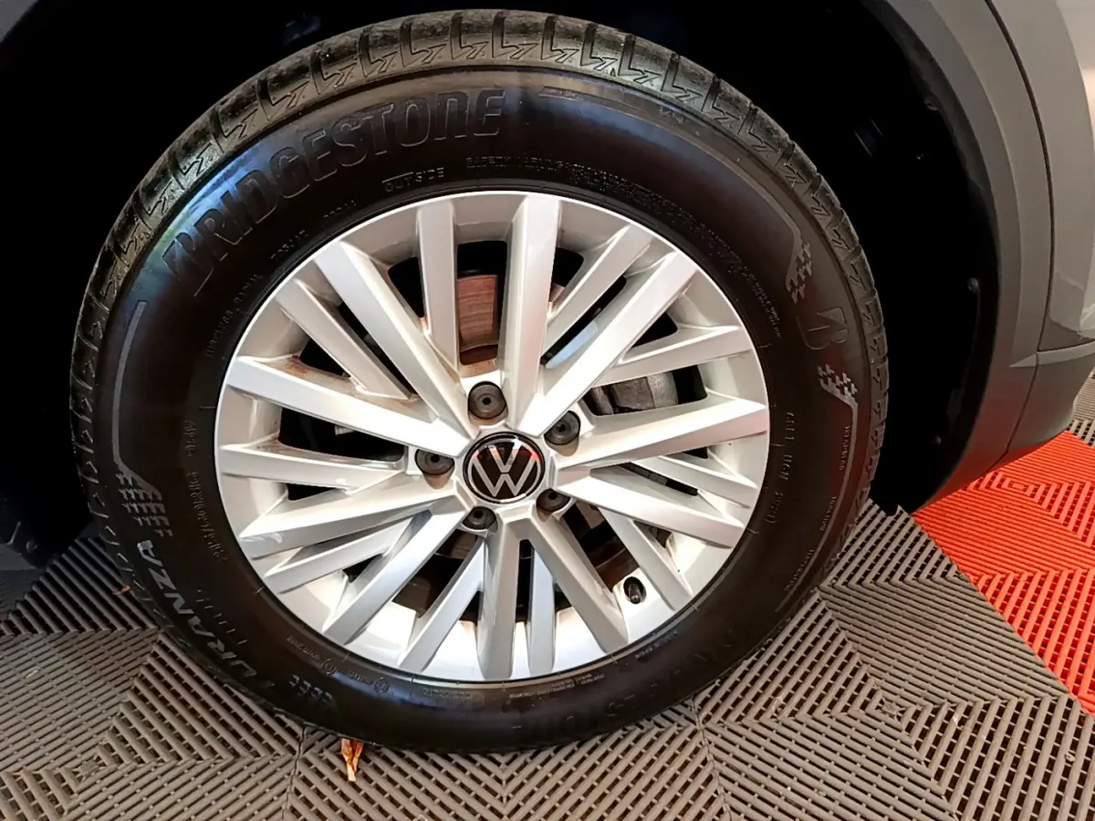 Gros plan sur la roue avant droite du Volkswagen T-Roc gris foncé, mettant en valeur la jante alliage et le pneu Bridgestone.
