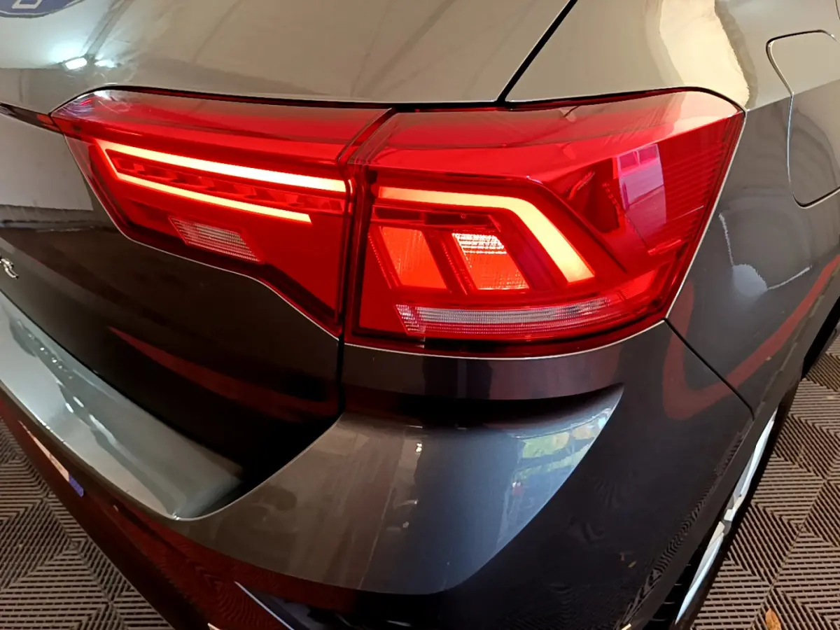 Gros plan sur le feu arrière droit d’un Volkswagen T-Roc gris foncé 2021, soulignant les lignes LED distinctives.