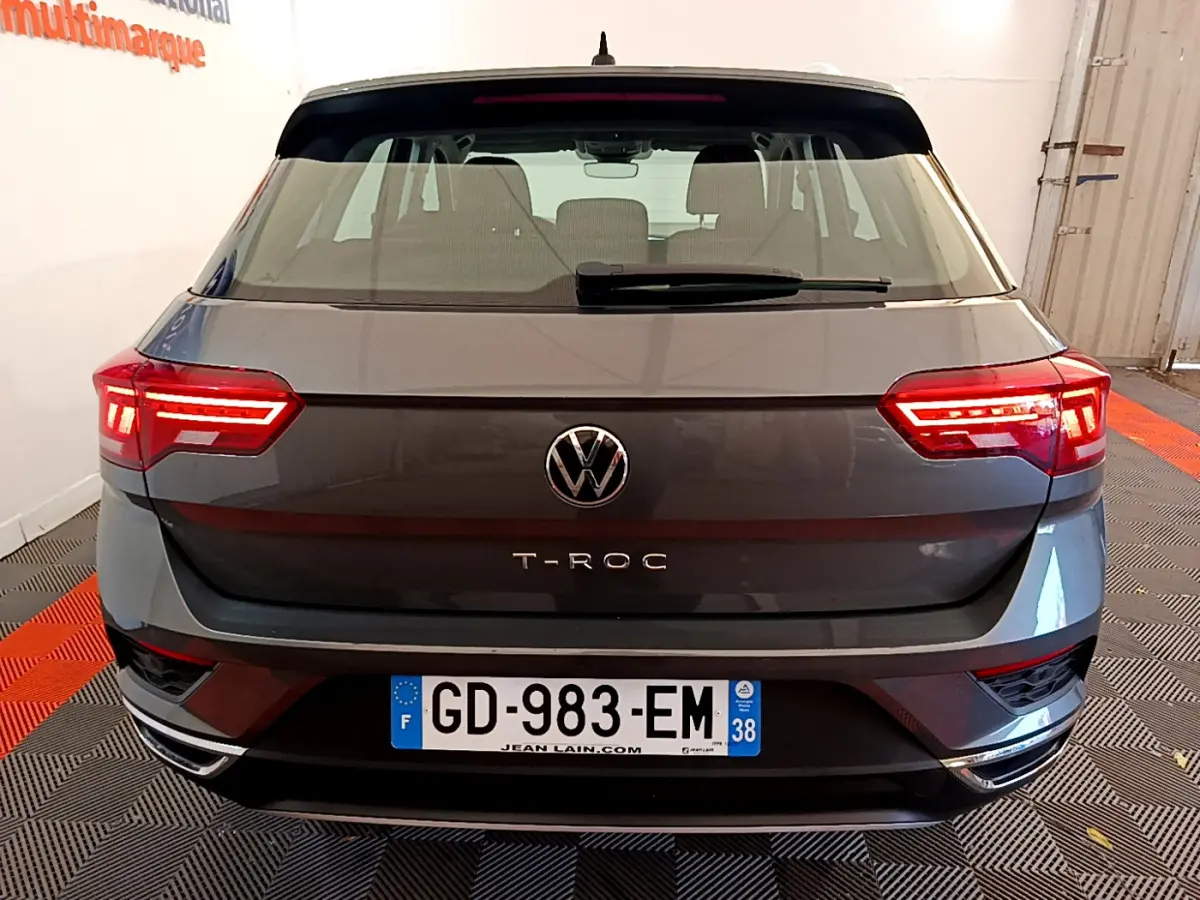 Vue arrière du Volkswagen T-Roc gris foncé 2021 avec feux LED allumés et plaque d'immatriculation française visible.