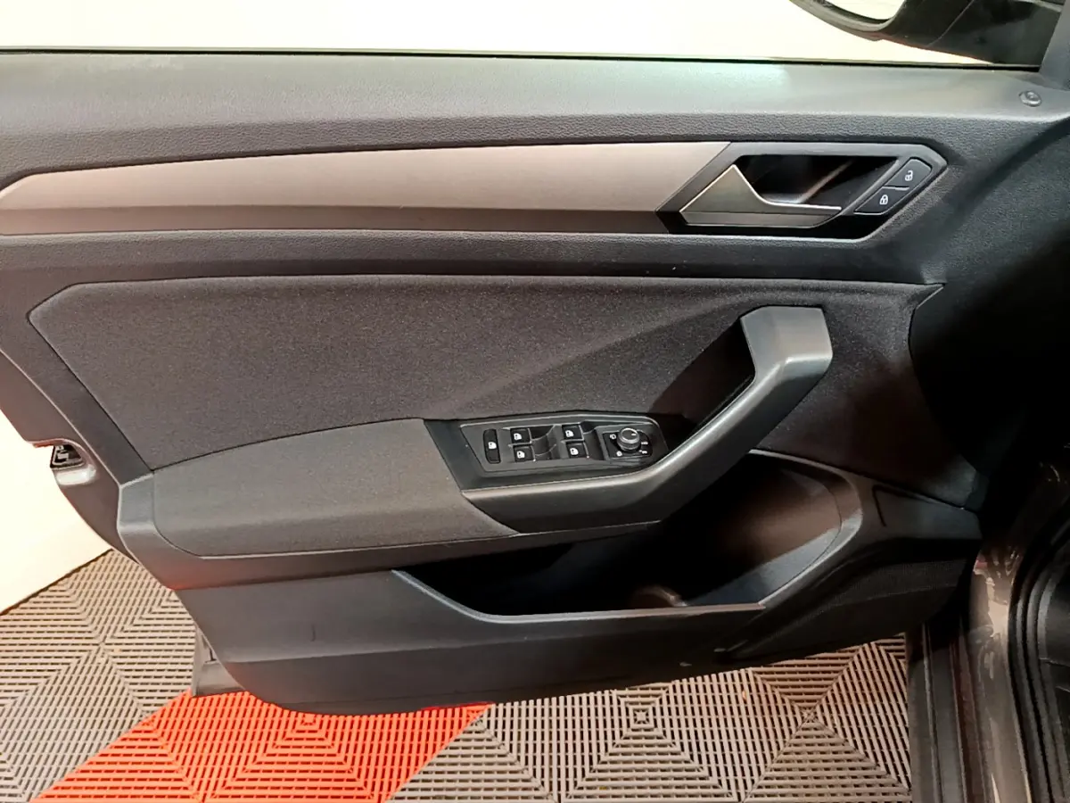Vue intérieure côté gauche de la porte avant d’un Volkswagen T-Roc gris foncé avec commandes de vitres et serrure.
