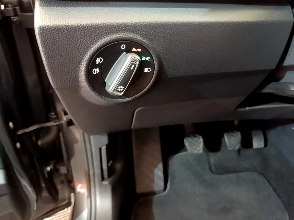 Détail intérieur côté gauche du Volkswagen T-Roc 2021, bouton de commande des phares et pédales visibles.