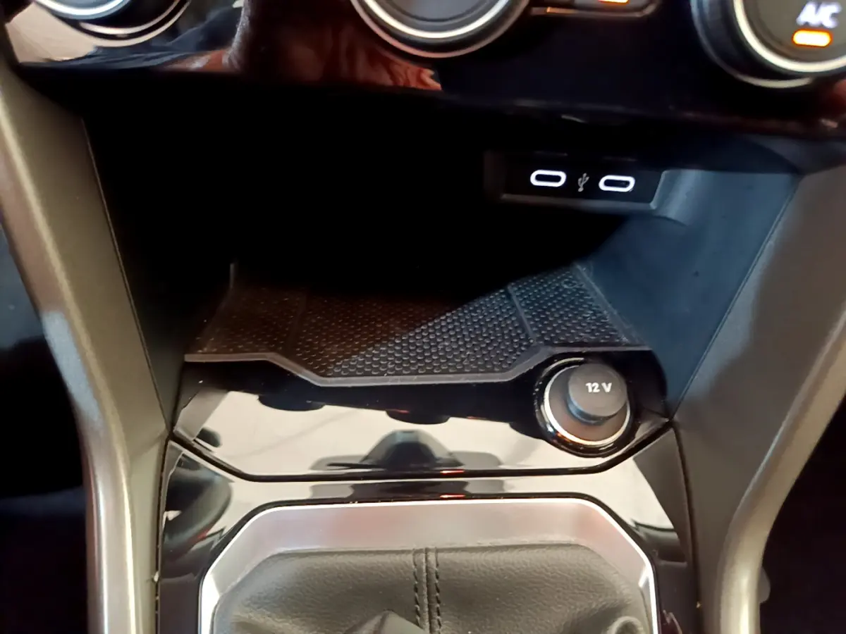 Gros plan sur la console centrale du Volkswagen T-Roc 2021, avec prise 12V et ports USB éclairés.