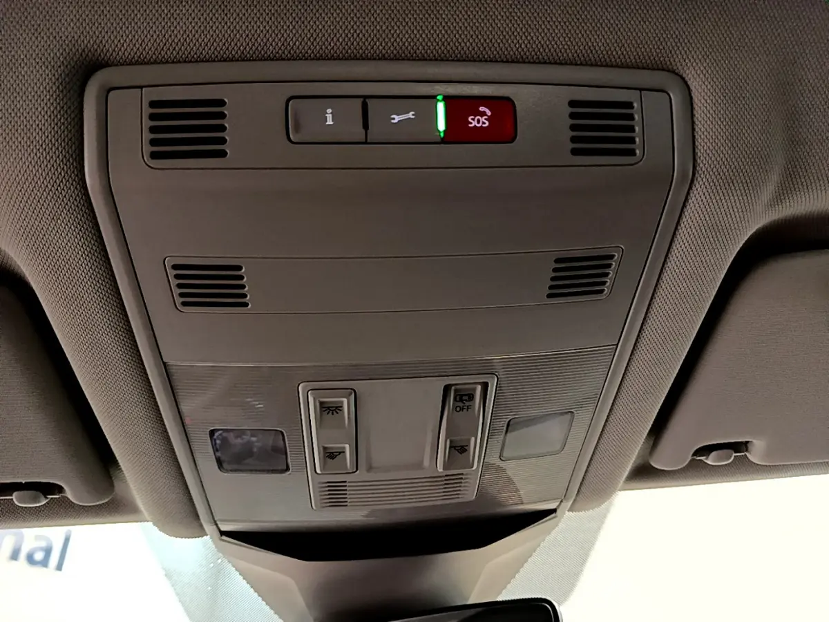 Vue intérieure du plafonnier gris clair du Volkswagen T-Roc 1.0 TSI 110 Lounge Business avec boutons de commande et alerte SOS allumée.
