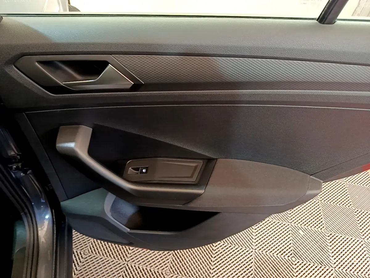 Vue rapprochée de la porte avant gauche gris foncé du Volkswagen T-Roc 2021 avec poignée et commande de vitre électrique.