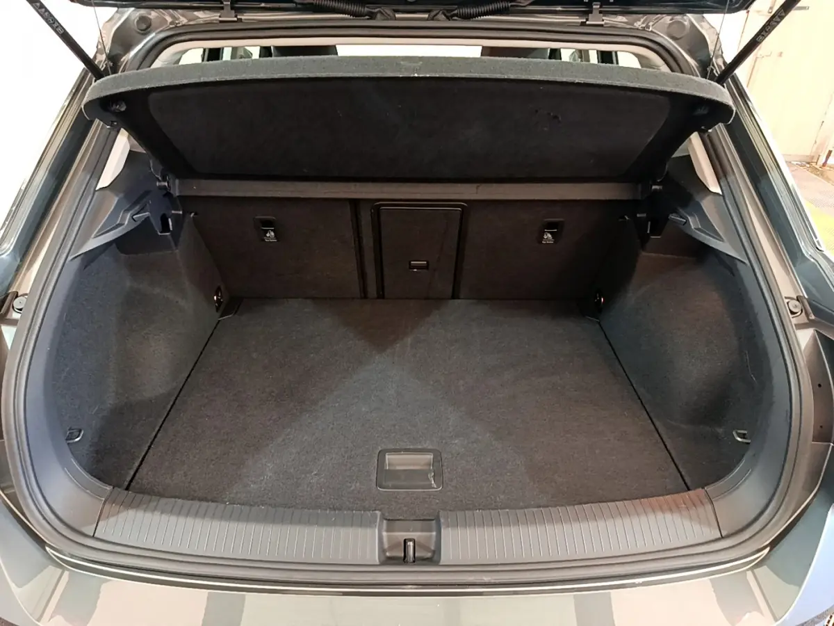 Coffre ouvert vu de l'arrière d'un Volkswagen T-Roc gris foncé, montrant un espace de chargement propre et spacieux.