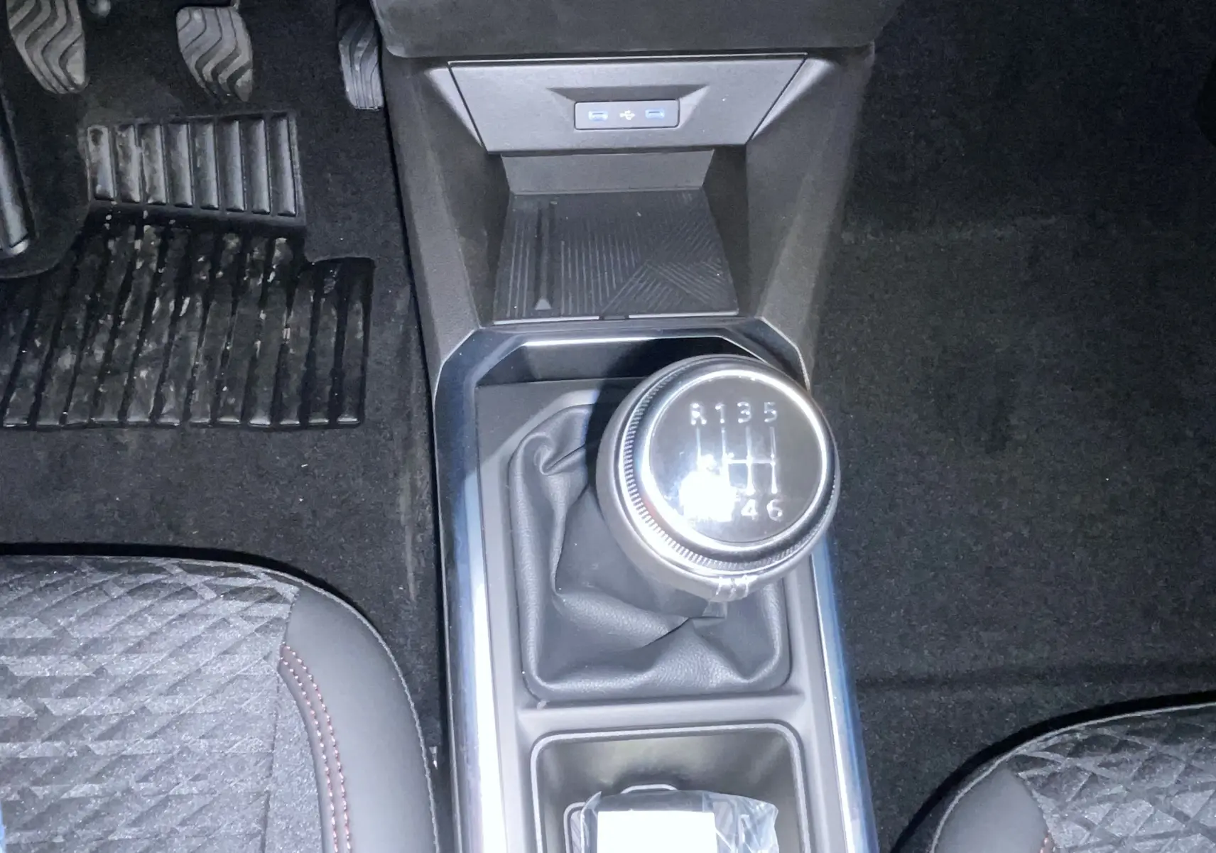 Gros plan sur les commandes au volant gauche de la Renault Clio VI gris Rafale, avec affichage digital en arrière-plan.