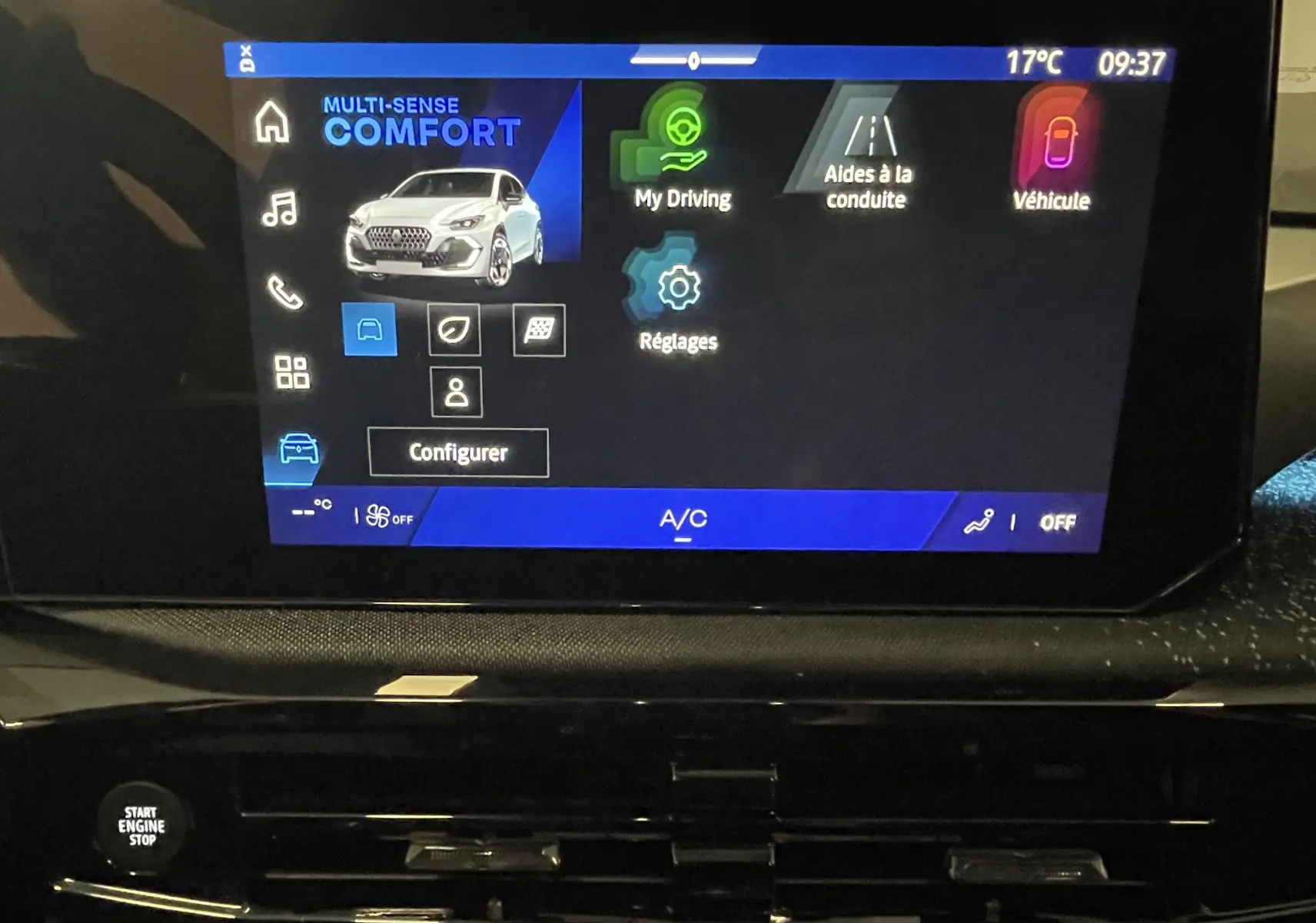 Gros plan sur les commandes de réglage des phares et désactivation du start-stop dans l’habitacle noir d’une Renault Clio VI gris Rafale.
