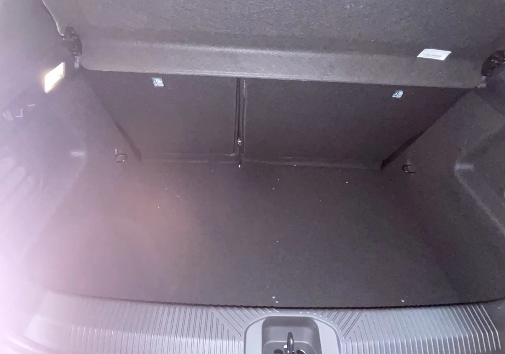 Coffre ouvert de Renault Clio VI TCe 115ch Techno 2026, vue plongeante sur espace gris Rafale métal sans roue de secours.