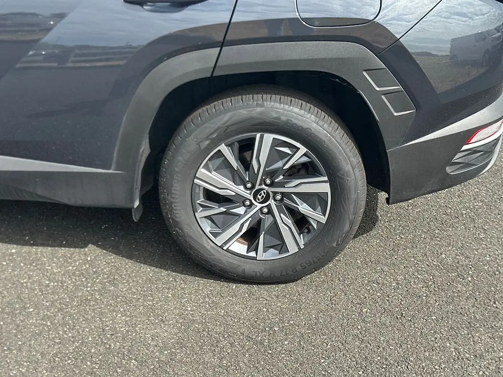 Gros plan sur la roue arrière droite d’un Hyundai Tucson gris 2023, soulignant la jante en alliage au design géométrique.