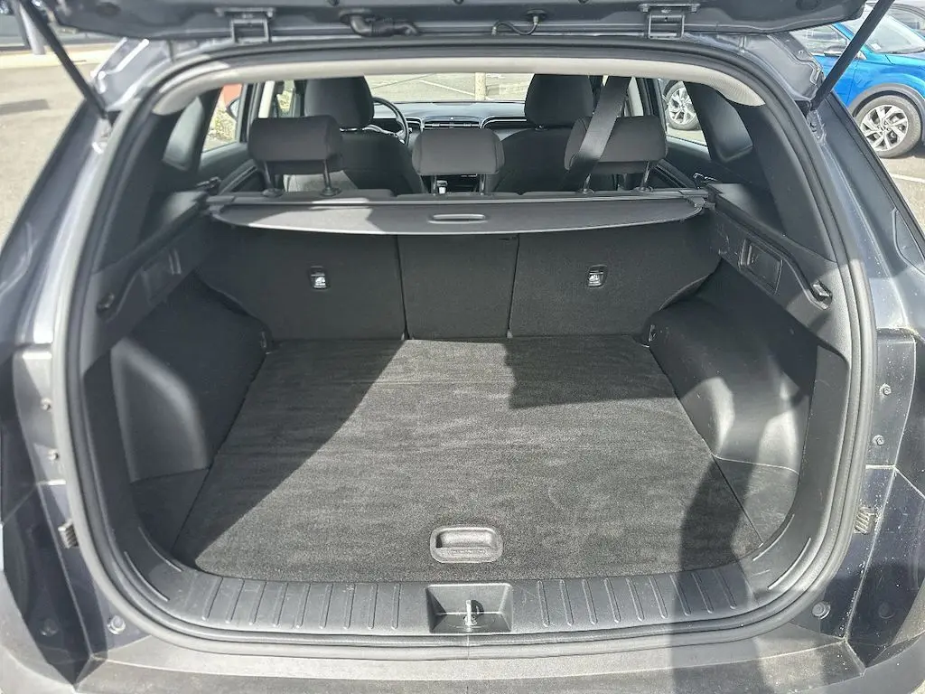 Coffre ouvert vu de l'arrière d'un Hyundai Tucson gris 2023, montrant l'espace de chargement et la plage arrière.