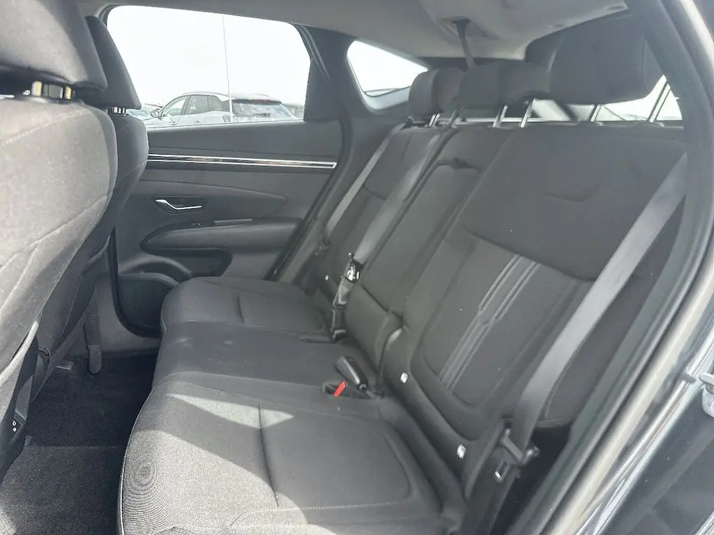 Vue intérieure côté droit des sièges arrière noirs du Hyundai Tucson 2023 gris, montrant l'espace et les appuie-têtes réglables.