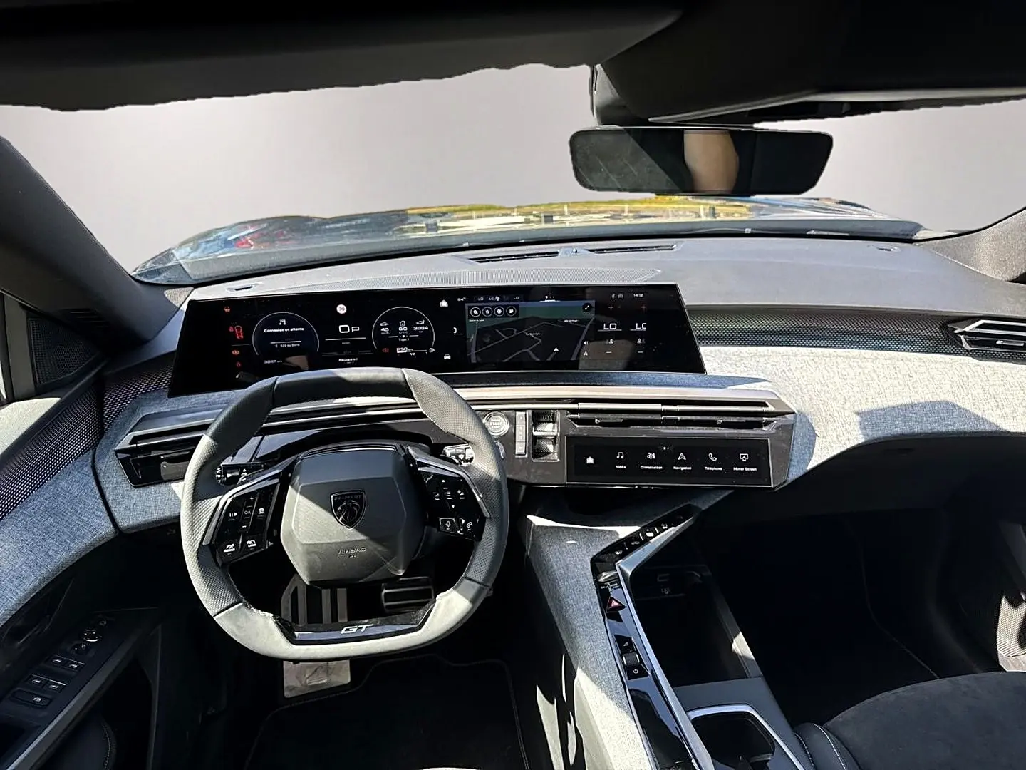 Vue intérieure avant du Peugeot 5008 Hybrid 145 GT 2025, volant cuir GT et tableau de bord numérique avec finition grise.
