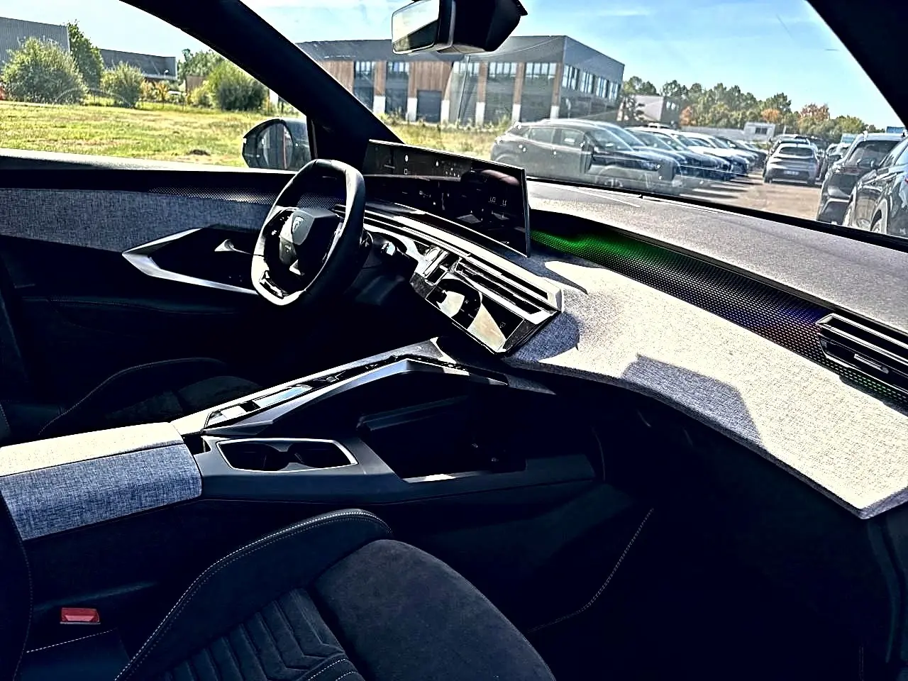 Vue intérieure côté conducteur du Peugeot 5008 Hybrid 145 GT 2025, tableau de bord clair et volant compact noir.
