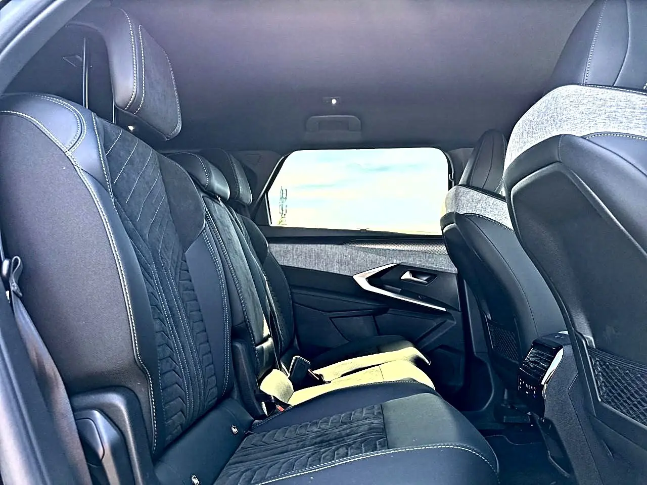 Vue intérieure côté gauche des sièges arrière noirs et gris du Peugeot 5008 Hybrid 145 GT avec appuie-têtes et finitions tissu et cuir.