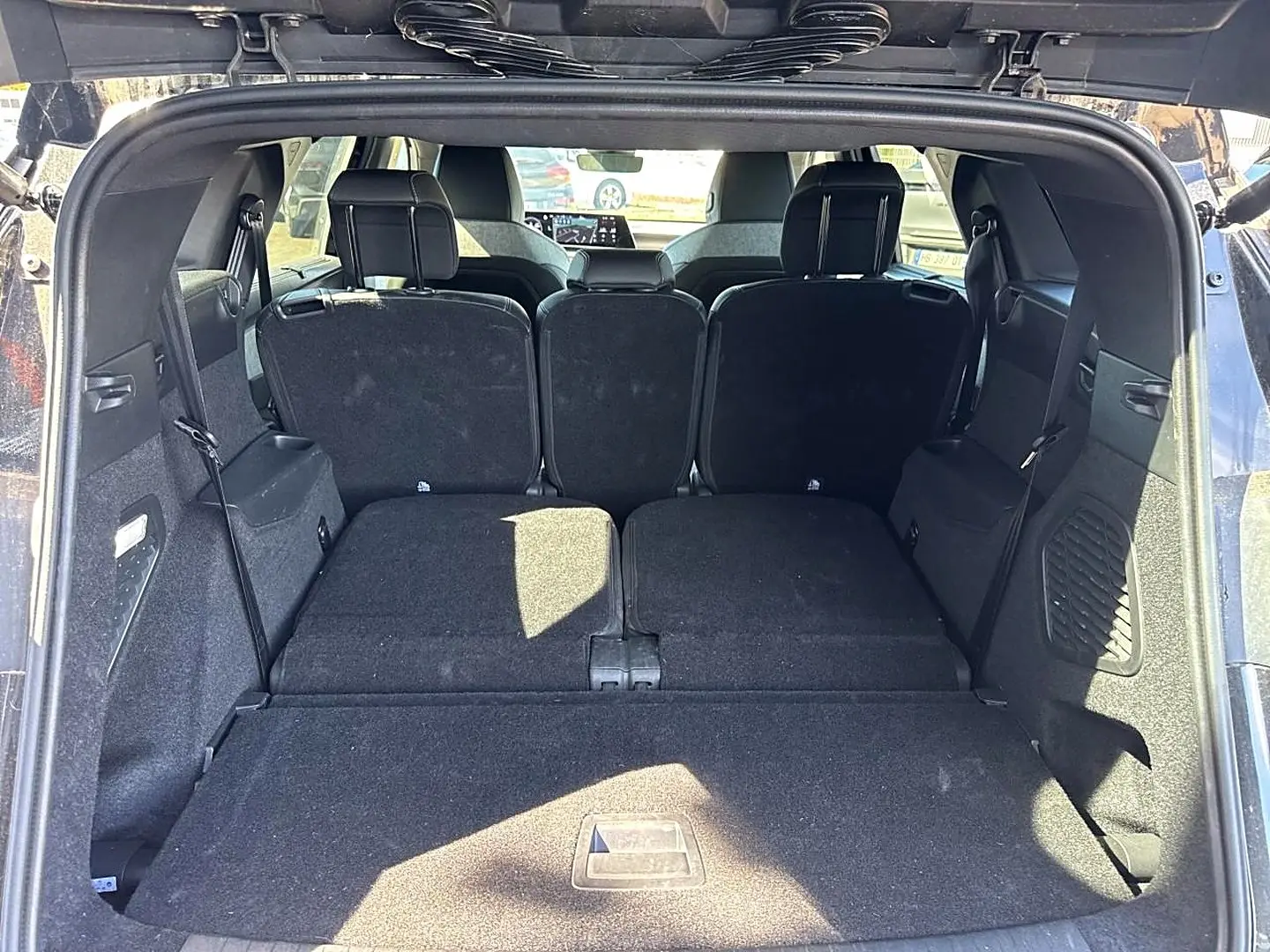 Vue arrière du coffre ouvert du Peugeot 5008 noir avec banquette arrière partiellement rabattue et espace de chargement plat.