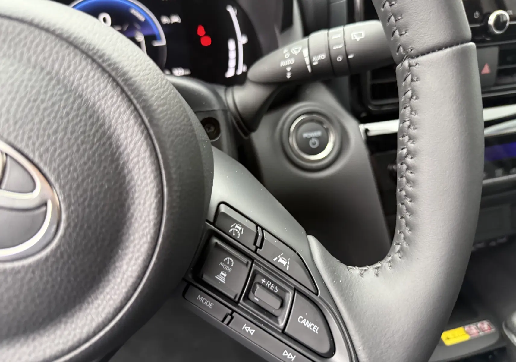 Gros plan sur le volant noir de la Toyota Yaris Cross 130 CH Design 2025, montrant les commandes de régulateur de vitesse.