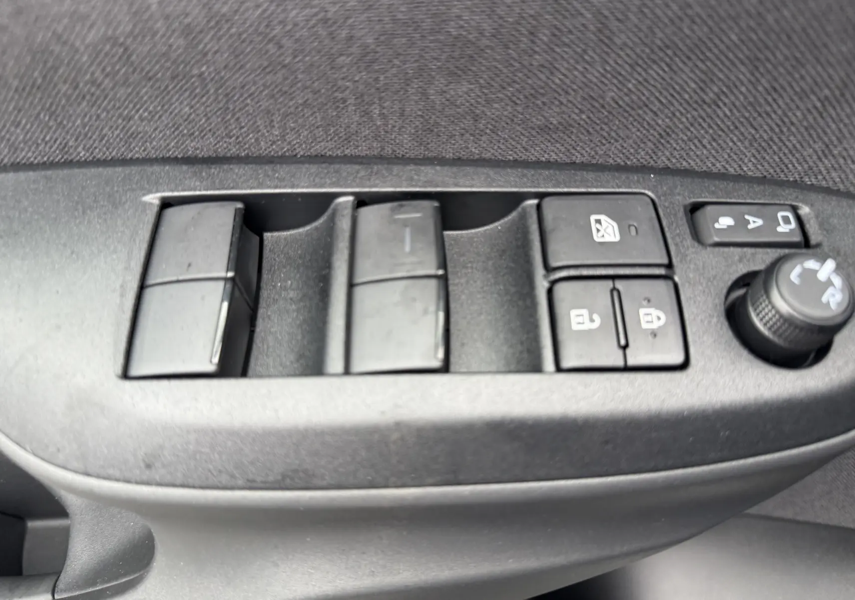 Panneau de commandes des vitres et rétroviseurs côté gauche intérieur d'une Toyota Yaris Cross blanche hybride 2025.