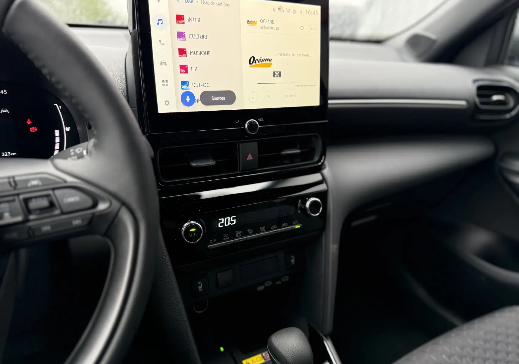 Vue intérieure centrée sur la console centrale et l'écran tactile du Toyota Yaris Cross blanc pur 2025, avec volant partiel visible.