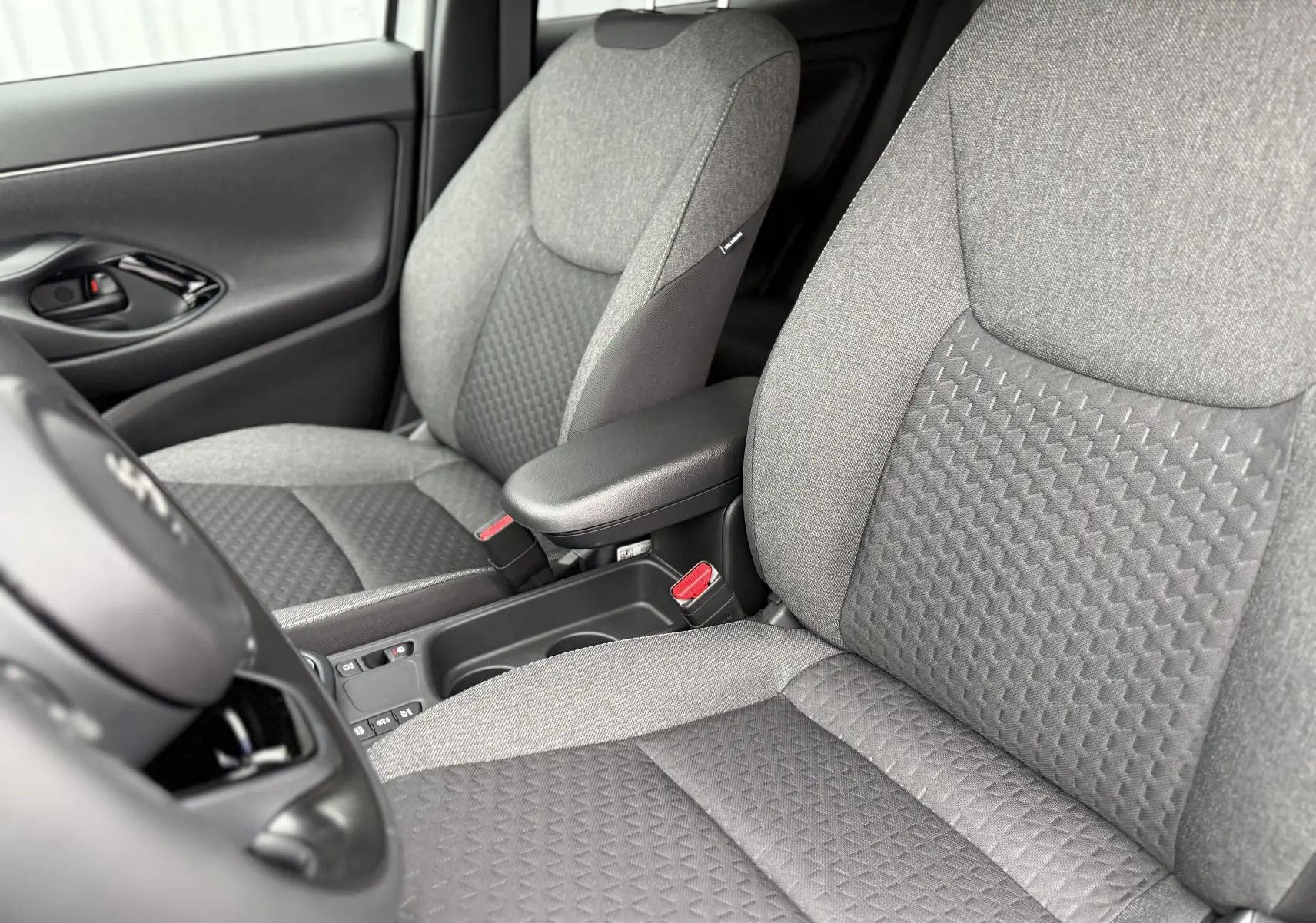 Vue rapprochée des sièges avant gris texturés de la Toyota Yaris Cross 130 CH DESIGN MY25, intérieur moderne et soigné.