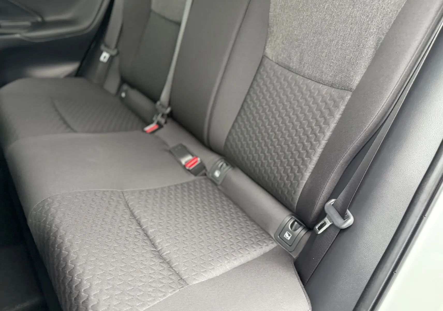 Vue rapprochée des sièges arrière gris foncé au tissu texturé d'une Toyota Yaris Cross blanche 2025.