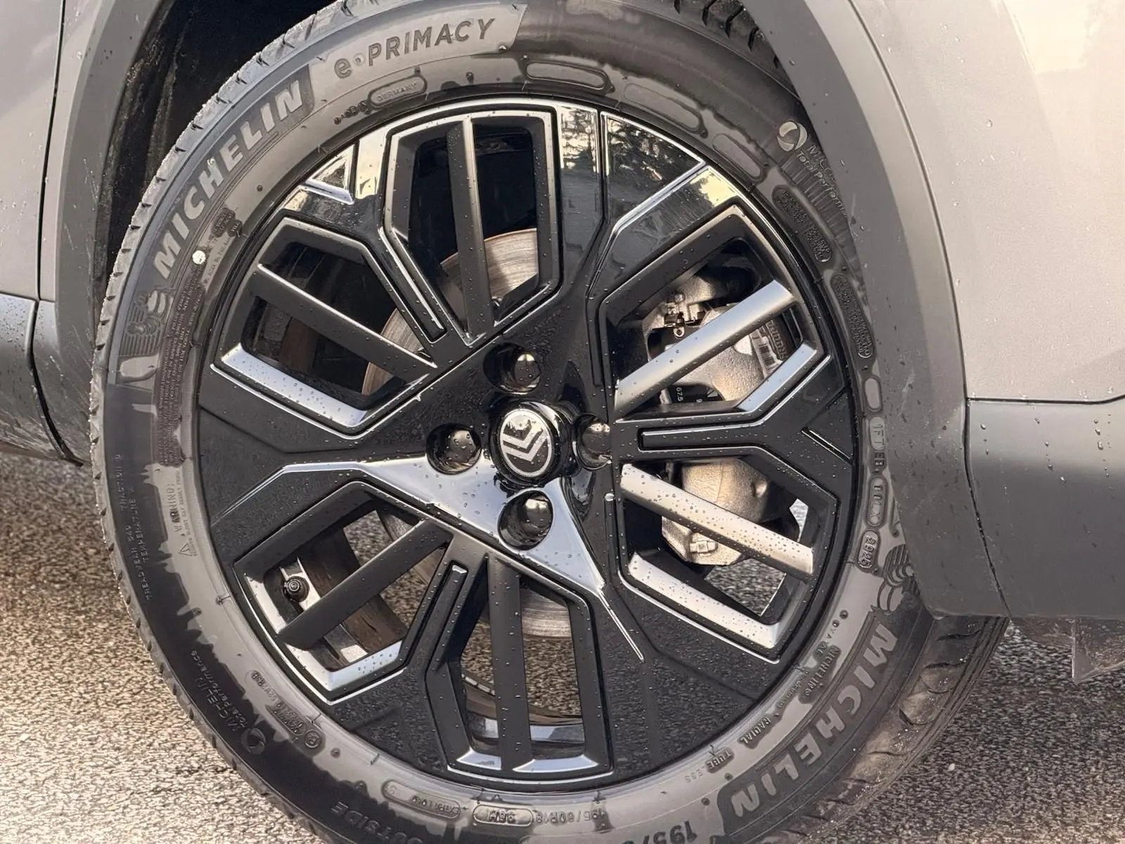 Gros plan sur la roue avant droite d’une Citroën C4 hybride gris Mercury avec jante noire et argentée au design géométrique.