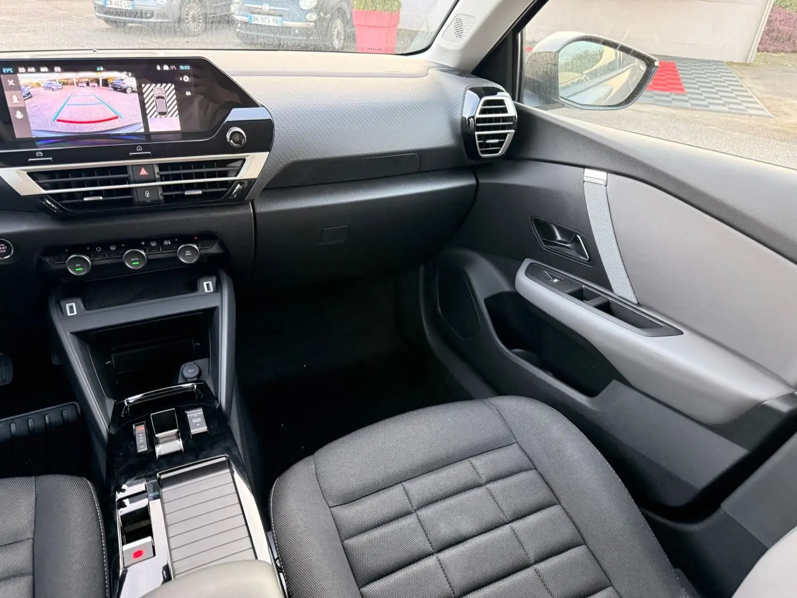 Intérieur côté passager de la Citroën C4 hybride gris Mercury 2025, avec tableau de bord moderne et écran tactile affichant la caméra de recul.