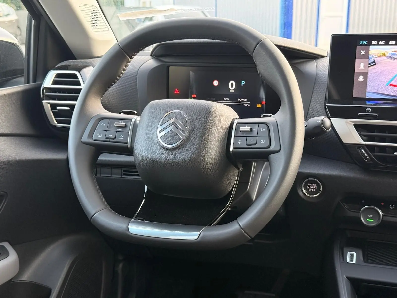 Vue intérieure centrée sur le volant cuir noir du Citroën C4 hybride 2025 avec tableau de bord numérique et écran tactile.