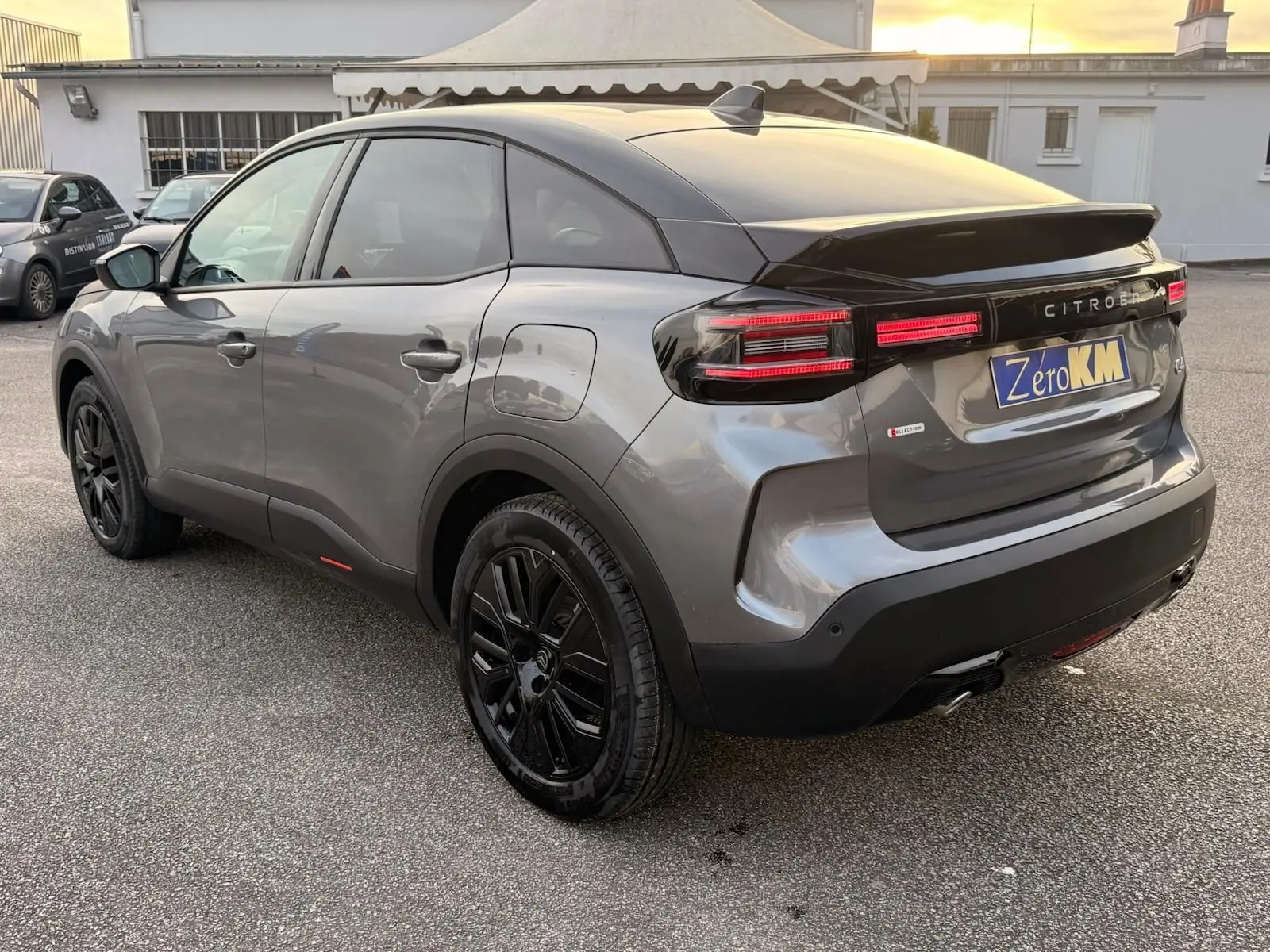 Vue 3/4 arrière droite d'une Citroën C4 hybride gris Mercury avec jantes noires et feux arrière LED distinctifs.