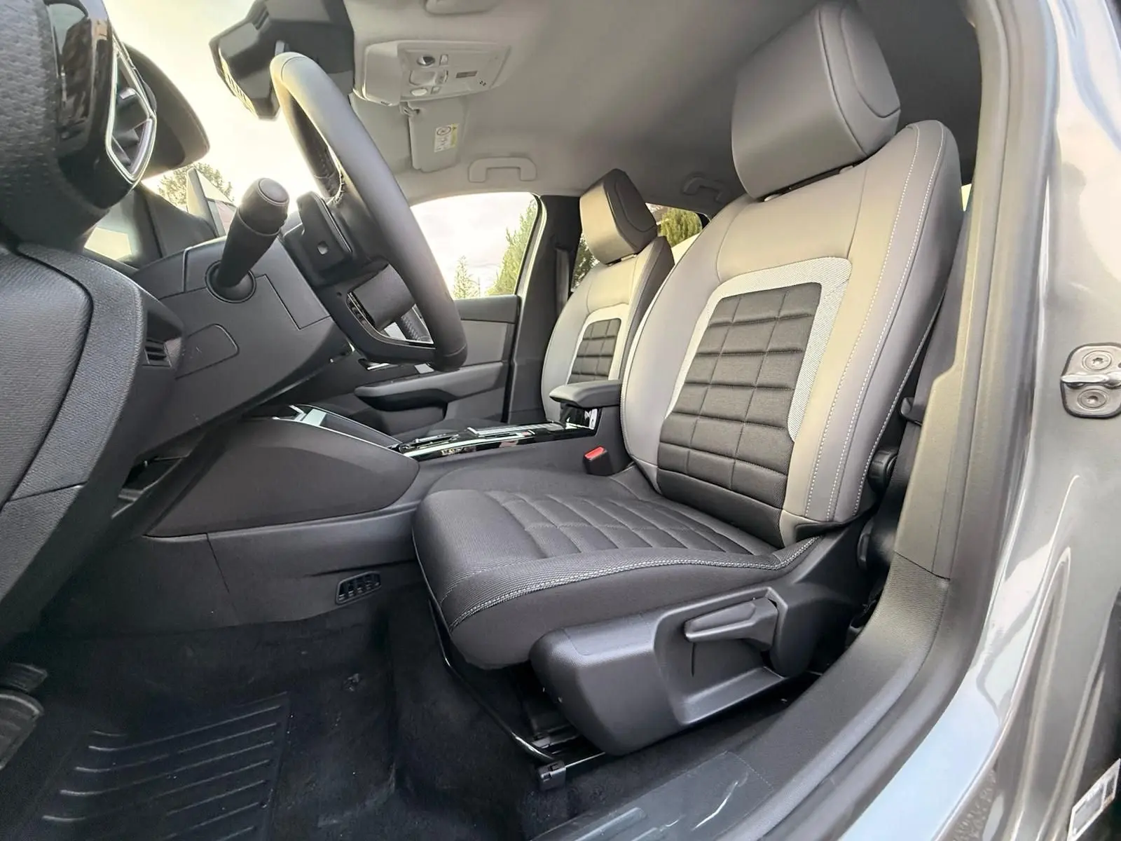 Vue intérieure côté conducteur de la Citroën C4 hybride gris Mercury, mettant en valeur les sièges bi-matière et le volant moderne.