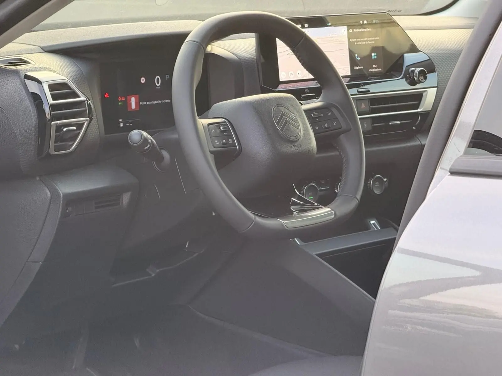 Vue intérieure côté conducteur de la Citroën C4 hybride gris Mercury, avec tableau de bord numérique et écran tactile central.