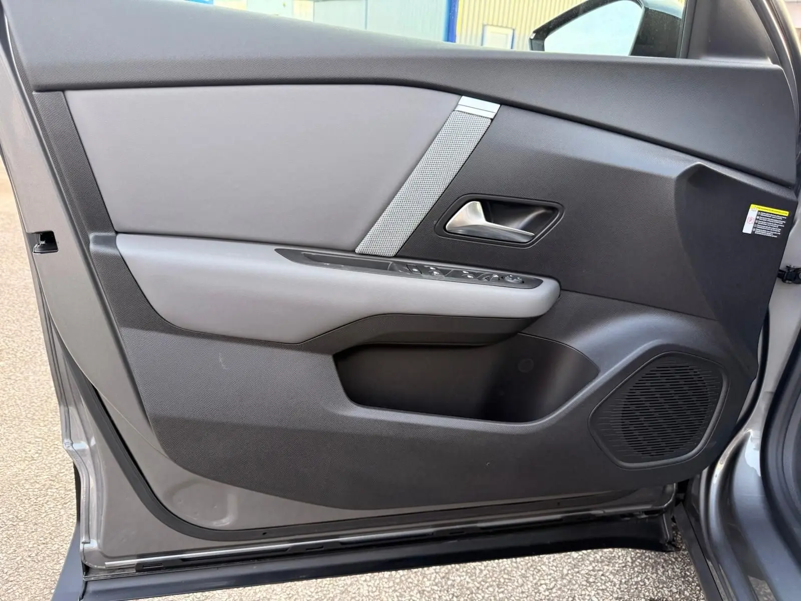 Vue intérieure côté gauche de la porte avant grise Mercury de la Citroën C4 hybride avec commandes et haut-parleur intégrés.