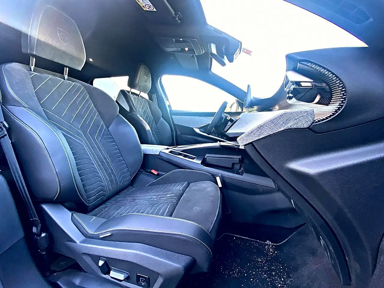 Vue intérieure côté passager avant du Peugeot 5008 Hybrid 145 GT e-dcs6 2025, sièges noirs avec surpiqûres et tableau de bord moderne.