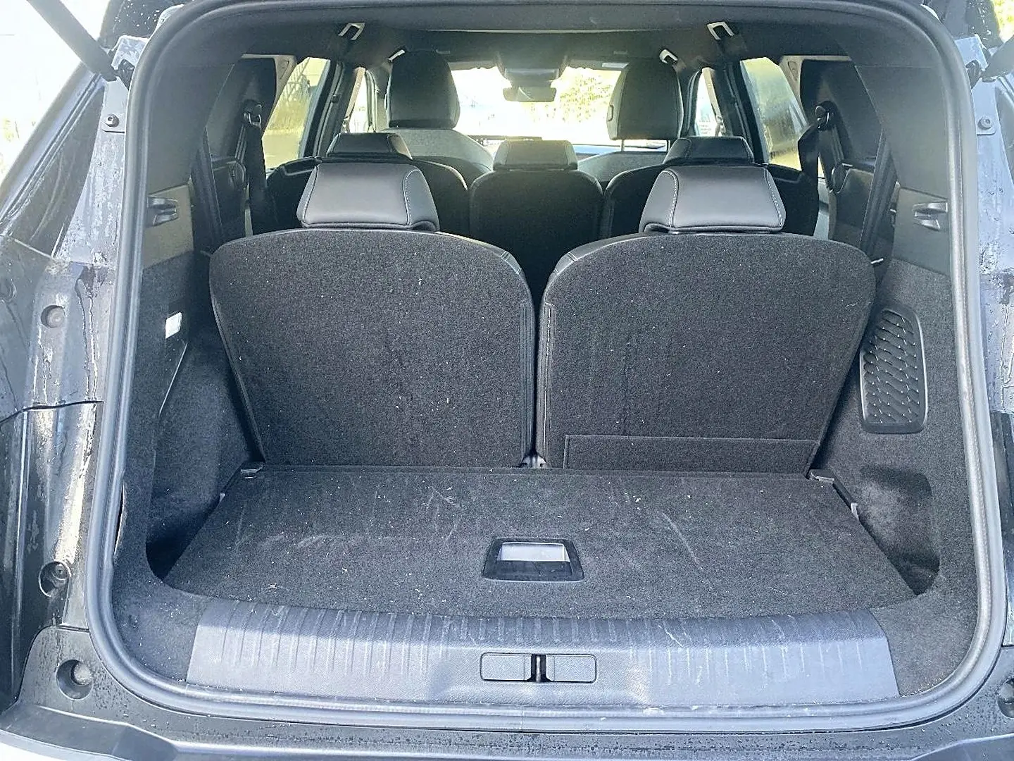 Vue arrière du coffre ouvert du Peugeot 5008 noir, montrant les sièges arrière relevés et l'espace de chargement.