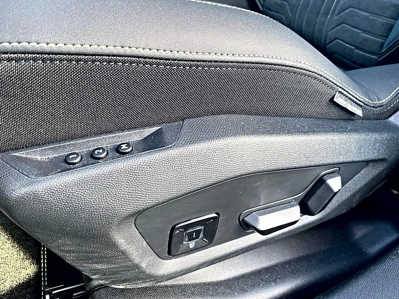 Détail des commandes de réglage électrique du siège avant gauche noir du Peugeot 5008 Hybrid 145 GT 2025.