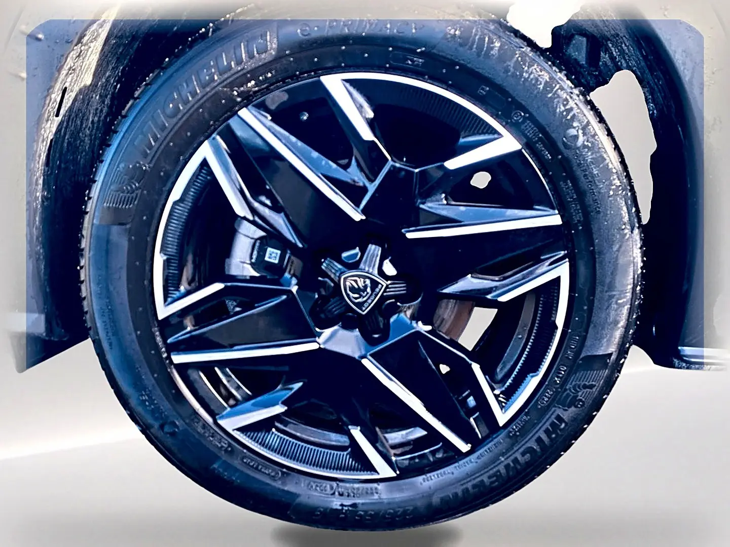 Gros plan sur la jante alu noire et argentée du Peugeot 5008 Hybrid 145 GT e-dcs6, pneu Michelin visible.