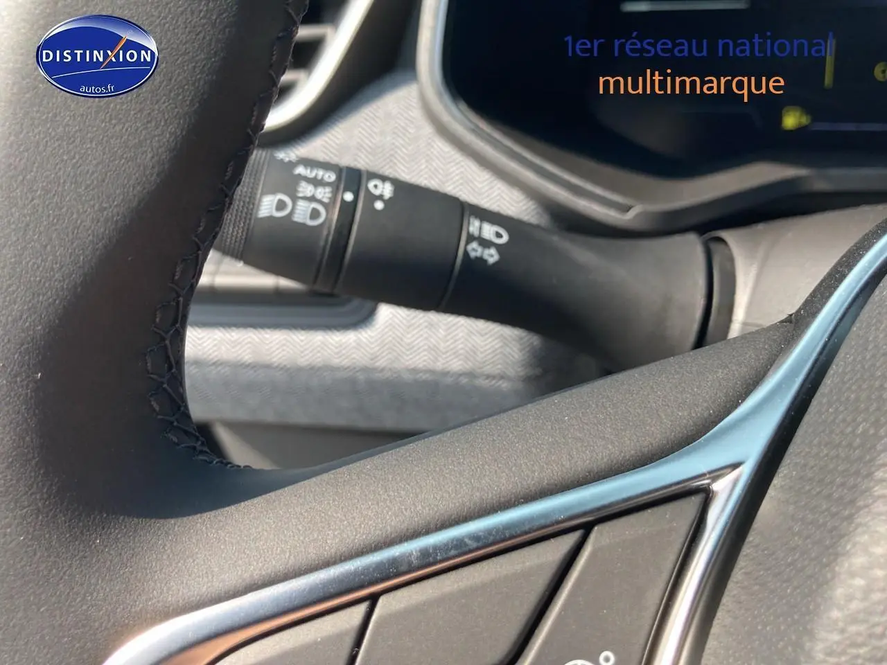 Gros plan sur les commandes au volant d'une Renault Clio V noire, mettant en valeur la finition techno et les détails du tableau de bord.