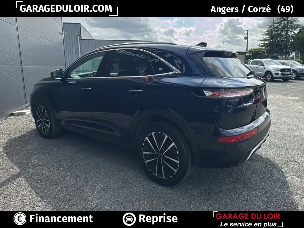 Vue 3/4 arrière droite d'un DS7 bleu saphir avec jantes alliage noires et vitres teintées sur parking extérieur.