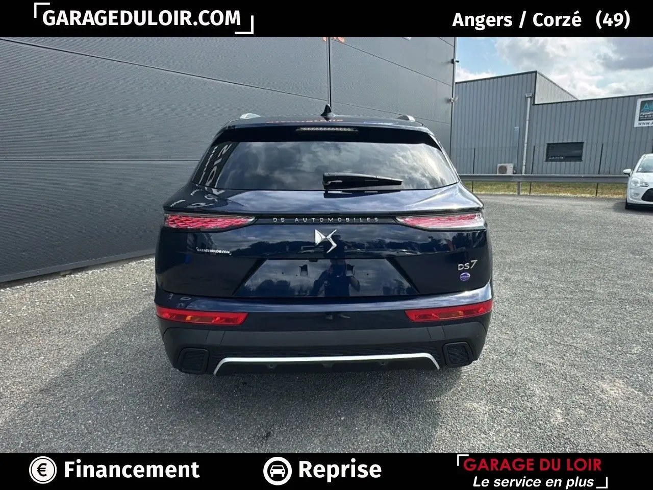 Vue arrière d'un DS7 bleu saphir avec feux 3D et logo DS Automobiles sur un parking extérieur.