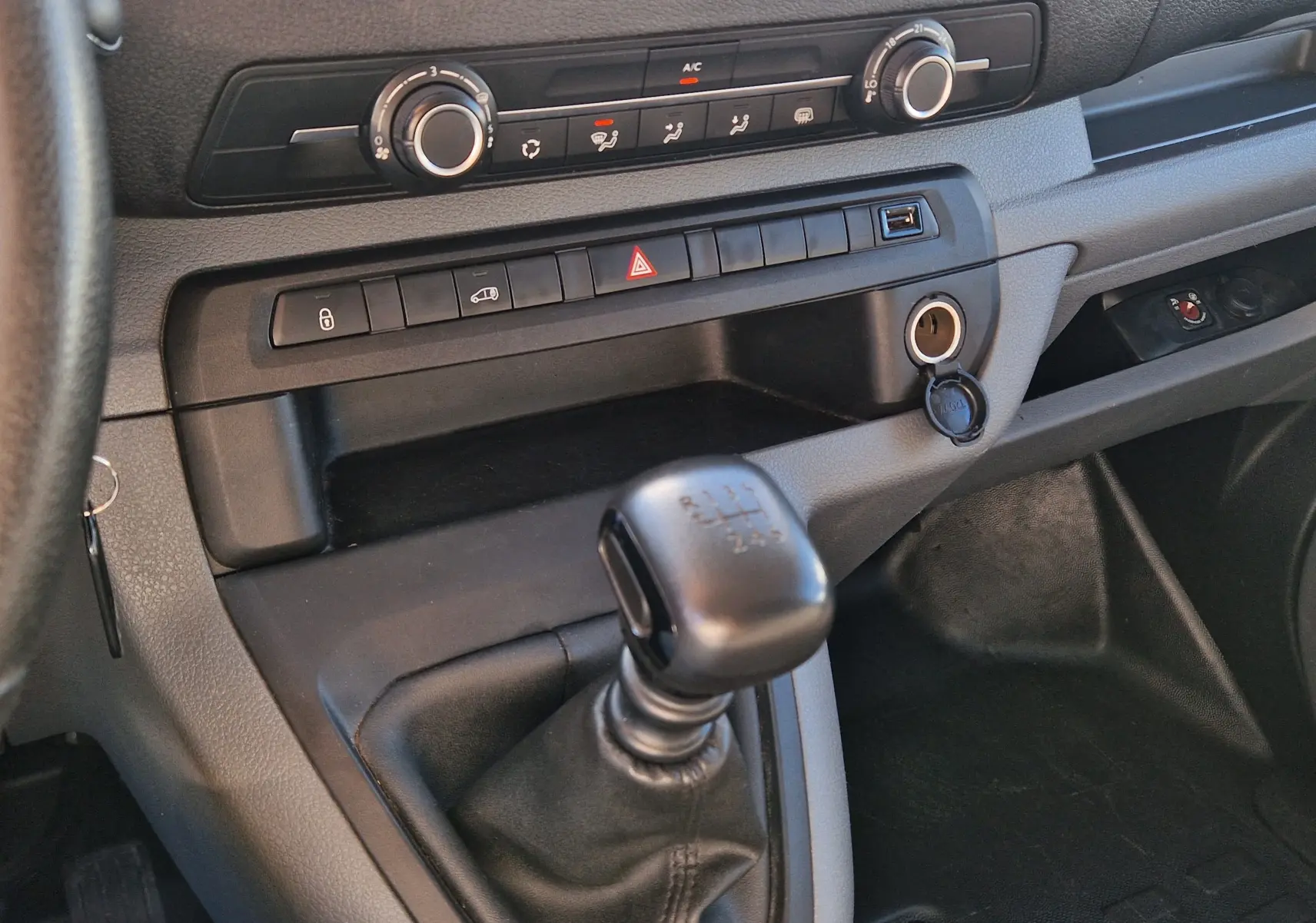 Vue rapprochée de la console centrale du Peugeot Expert Fourgon blanc 2020, avec levier de vitesse manuel et commandes climatisation.
