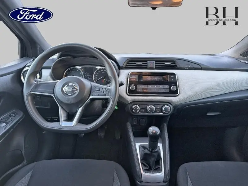 Intérieur avant d'une Nissan Micra gris acier 2018, vue centrée sur le volant, tableau de bord et levier de vitesses manuel.