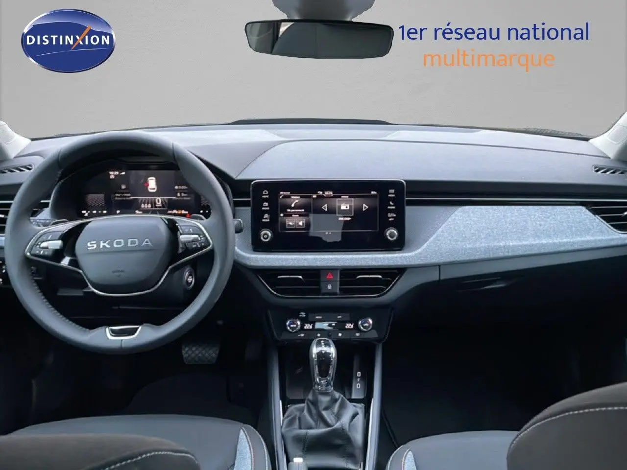 Vue intérieure frontale du tableau de bord gris clair et noir du Skoda Kamiq 2025 avec écran tactile et volant multifonction.