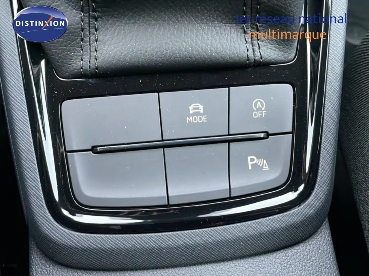 Gros plan sur les commandes de mode de conduite et assistance au stationnement du Skoda Kamiq gris graphite, intérieur tissu noir.