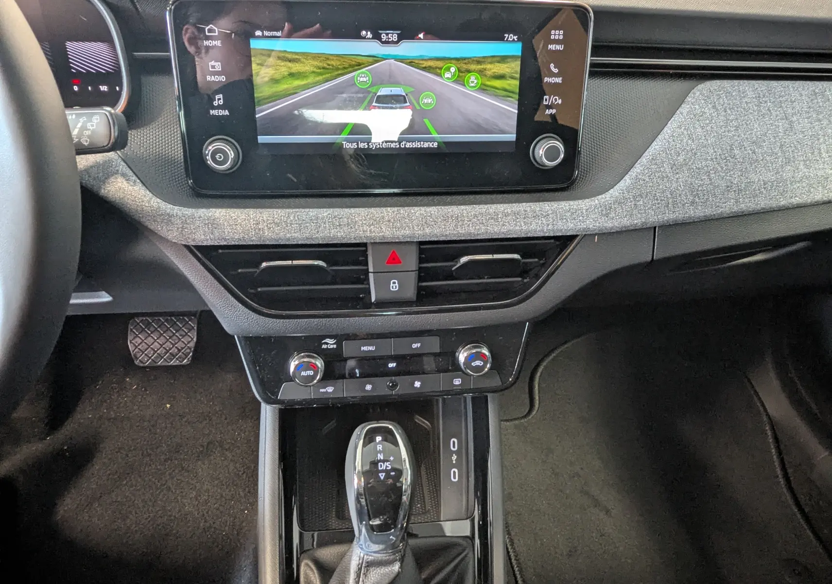 Vue intérieure centrée sur la console centrale et l'écran tactile du Skoda Kamiq 2025, avec levier de vitesses automatique.