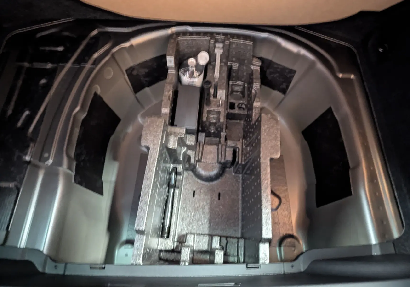 Vue plongeante sur le compartiment de rangement sous le coffre du Skoda Kamiq gris graphite, montrant l'emplacement pour outils.