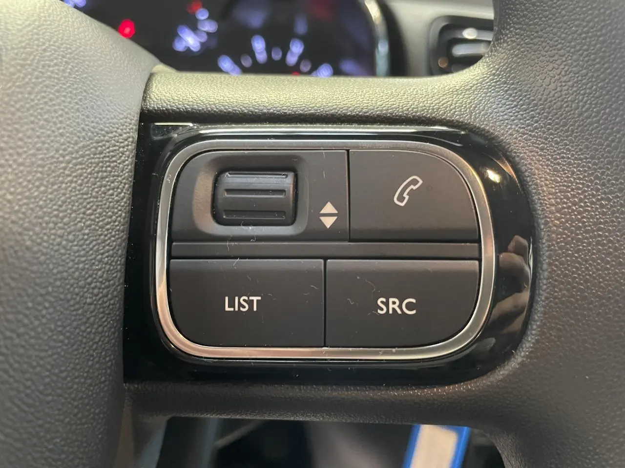 Gros plan sur les commandes audio au volant noir brillant de la Citroën C3 2024, boutons LIST et SRC visibles.