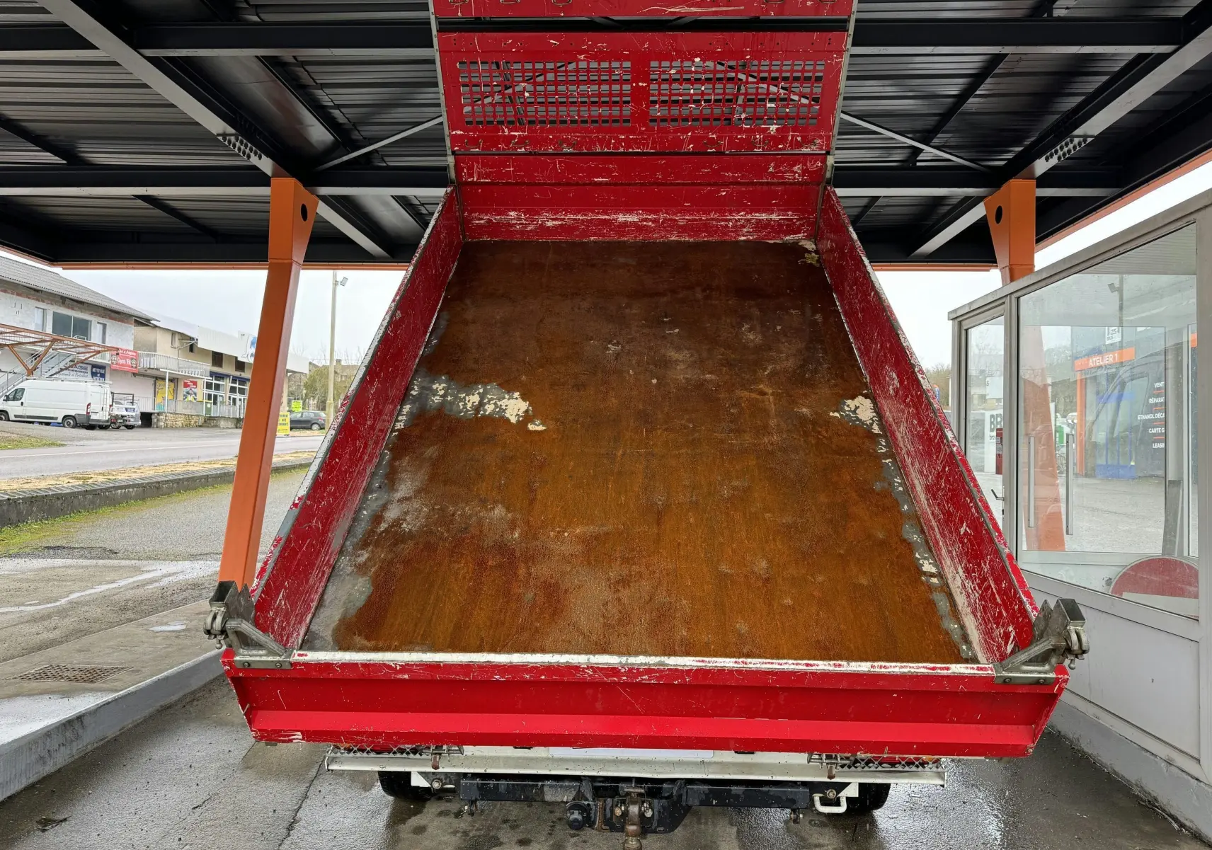 Vue arrière d'une benne rouge relevée d'un Citroën Jumper 2019 avec attelage et ridelles métalliques.